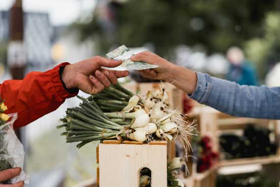 Farmers' Market Customer handing Cash to Farmer for Fresh Vegetables